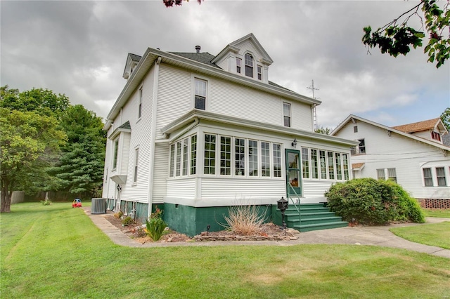 exterior space with a sunroom, cooling unit, and a lawn