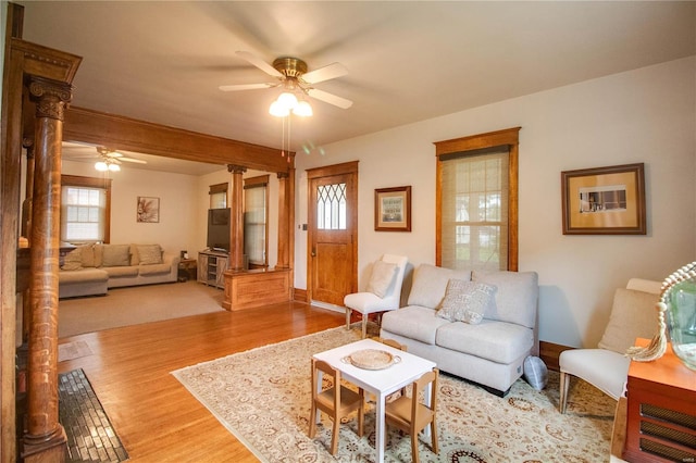 living room featuring light hardwood / wood-style floors, ornate columns, ceiling fan, and beamed ceiling