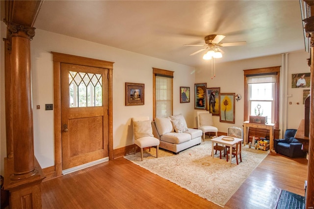 living room featuring wood-type flooring, decorative columns, and ceiling fan