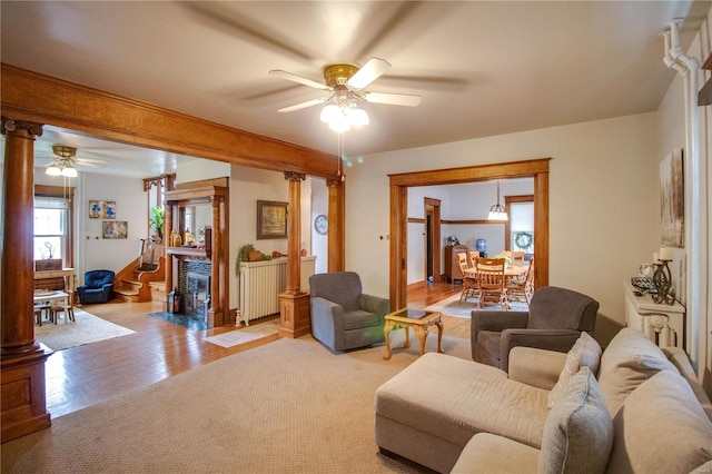 living room with ornate columns, light hardwood / wood-style flooring, and ceiling fan