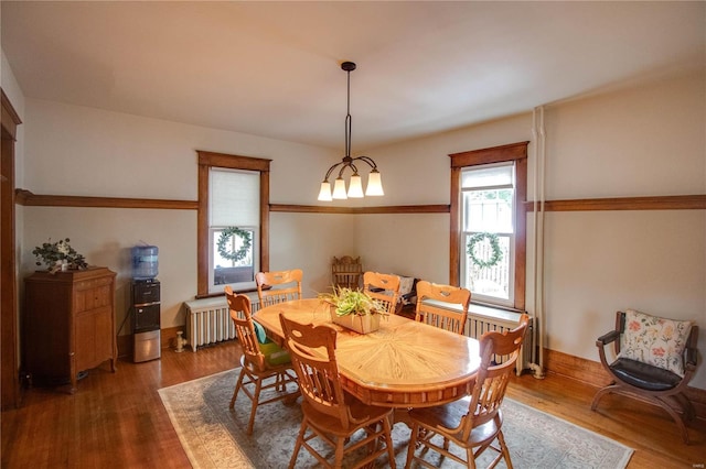 dining area featuring an inviting chandelier, hardwood / wood-style floors, and radiator heating unit