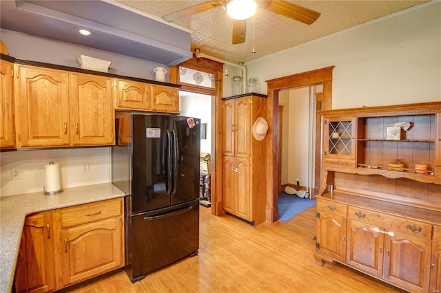 kitchen featuring light wood-type flooring, ceiling fan, black fridge, and ornamental molding