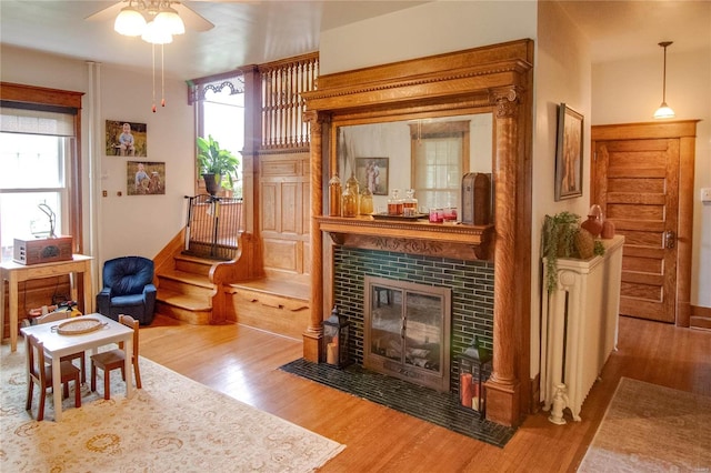 living room featuring hardwood / wood-style flooring, a tile fireplace, and ceiling fan