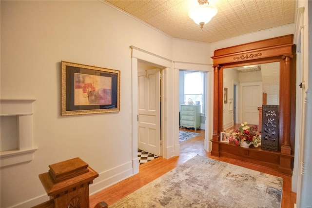 hallway with light hardwood / wood-style flooring and crown molding