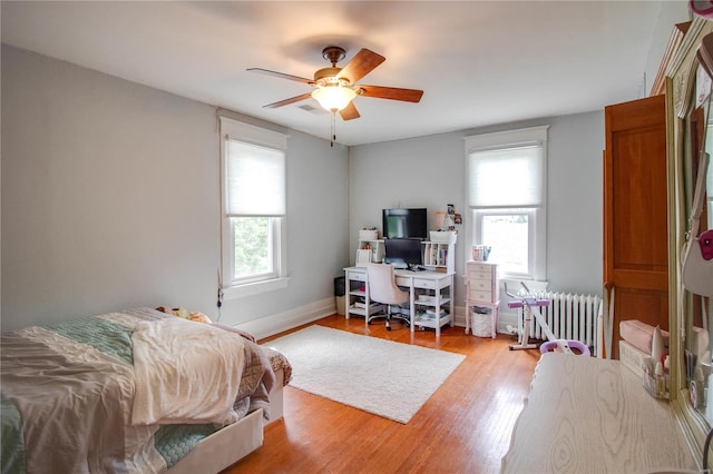 bedroom with light hardwood / wood-style floors, radiator heating unit, and ceiling fan