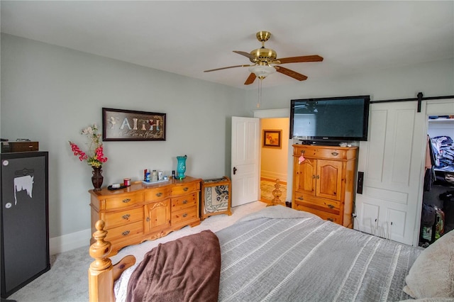 carpeted bedroom with ceiling fan and a barn door