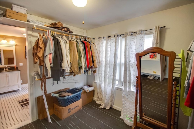 spacious closet with dark colored carpet and sink