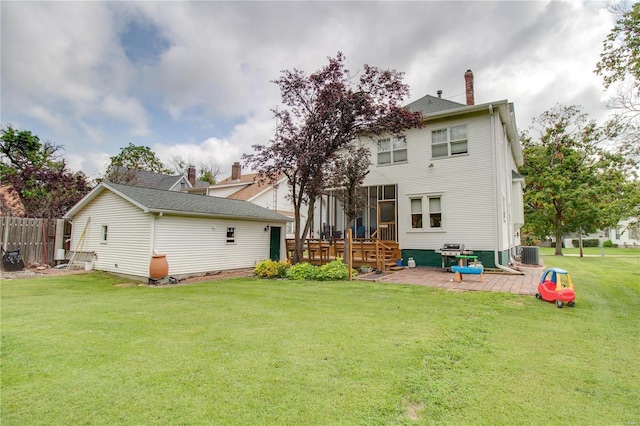 rear view of property featuring a yard, central AC, and a patio area