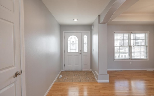 entrance foyer featuring arched walkways, baseboards, and light wood-style floors