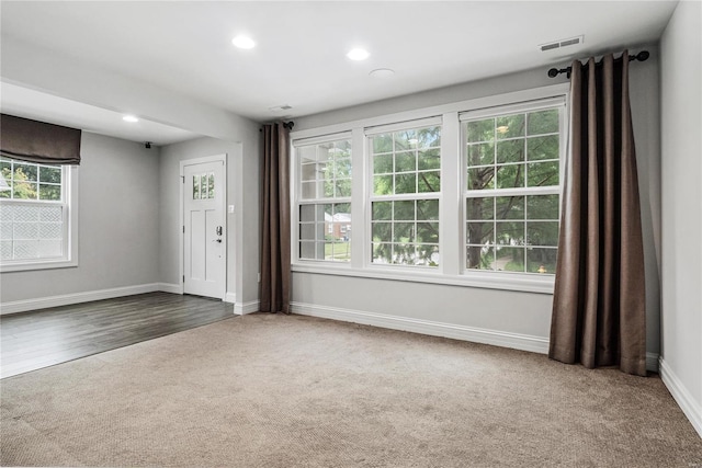 carpeted empty room with baseboards, visible vents, and recessed lighting