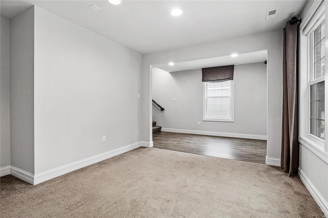 spare room with stairway, carpet, visible vents, and baseboards