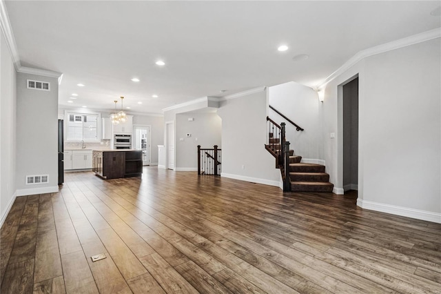 unfurnished living room with visible vents, crown molding, and wood finished floors