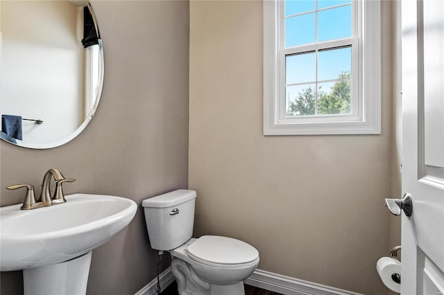 half bathroom featuring a sink, toilet, and baseboards