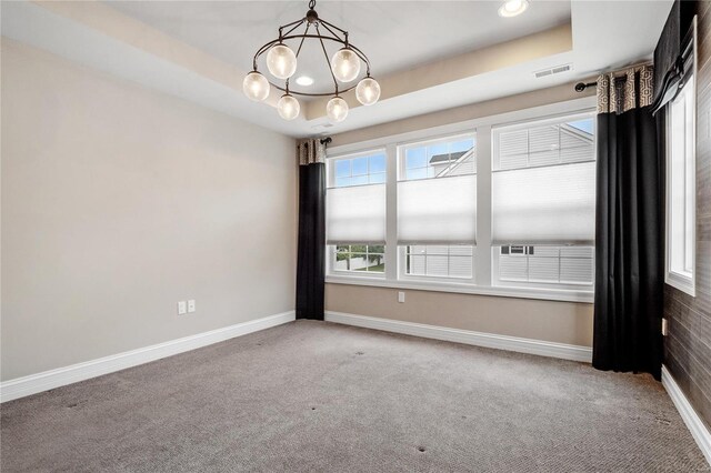 empty room featuring carpet, a raised ceiling, visible vents, and baseboards