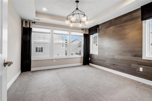 spare room with wooden walls, baseboards, a raised ceiling, and carpet flooring