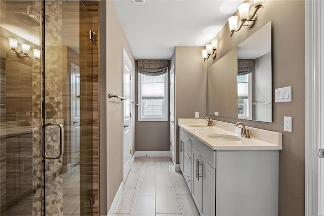 bathroom with double vanity, a stall shower, a sink, and baseboards