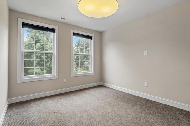 spare room featuring carpet flooring, visible vents, and baseboards