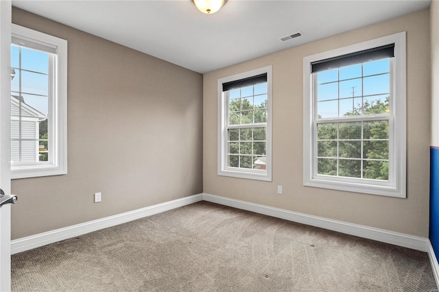 carpeted spare room featuring baseboards and visible vents