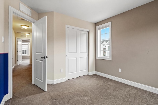 unfurnished bedroom featuring carpet floors, a closet, visible vents, and baseboards