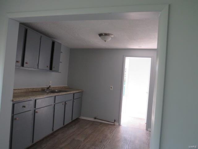 kitchen featuring light countertops, wood finished floors, and a sink