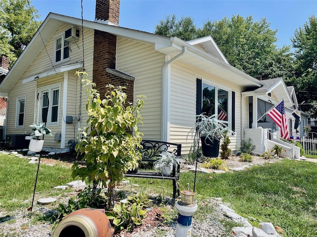 exterior space with central AC unit, an AC wall unit, and a front lawn