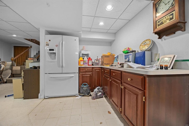 kitchen with white fridge with ice dispenser, light tile patterned flooring, and a drop ceiling