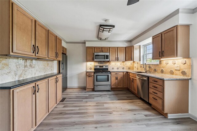 kitchen featuring stainless steel appliances, decorative backsplash, ornamental molding, sink, and light hardwood / wood-style flooring