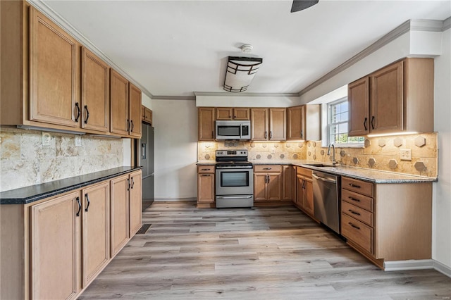 kitchen featuring sink, crown molding, stainless steel appliances, light hardwood / wood-style floors, and backsplash