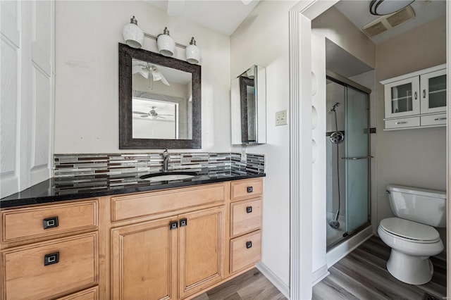 bathroom featuring walk in shower, vanity, toilet, and backsplash