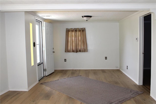 empty room with ornamental molding, a healthy amount of sunlight, a textured ceiling, and light wood-type flooring