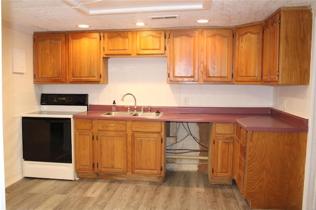 kitchen featuring sink, electric range, light hardwood / wood-style floors, and a textured ceiling