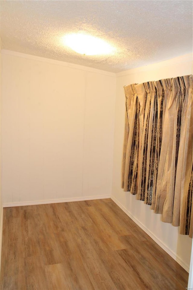 empty room with wood-type flooring and a textured ceiling