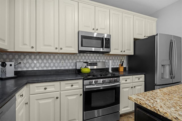 kitchen with appliances with stainless steel finishes, dark countertops, white cabinets, and tasteful backsplash