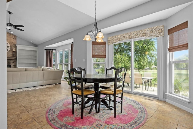 dining room with light tile patterned flooring, ceiling fan with notable chandelier, lofted ceiling, and a healthy amount of sunlight