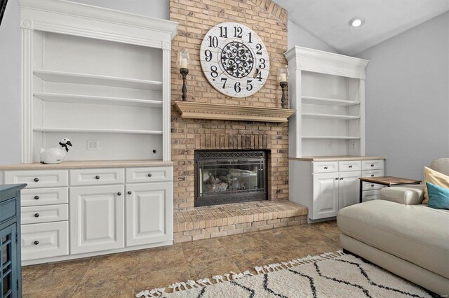 living room featuring dark tile patterned flooring, brick wall, lofted ceiling, and a brick fireplace