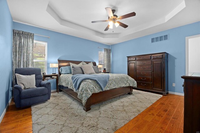 bedroom featuring ceiling fan, a raised ceiling, and hardwood / wood-style flooring