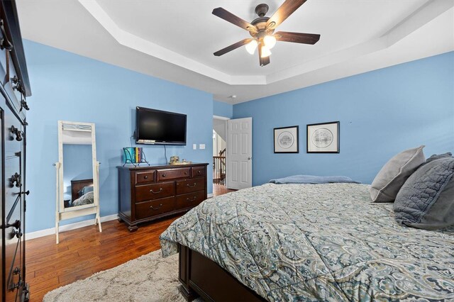 bedroom with a tray ceiling, hardwood / wood-style floors, and ceiling fan