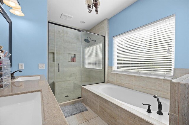 bathroom featuring tile patterned floors, dual sinks, and separate shower and tub