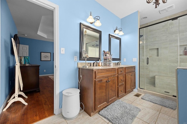 bathroom featuring dual vanity, a shower with shower door, and tile patterned flooring