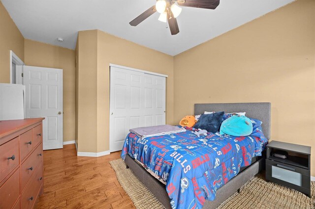 bedroom featuring ceiling fan, white refrigerator, light hardwood / wood-style floors, and a closet