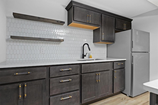 kitchen with freestanding refrigerator, light countertops, a sink, and open shelves