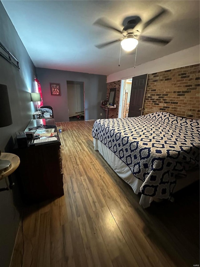 bedroom featuring hardwood / wood-style floors, ceiling fan, and brick wall