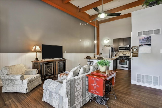 living room featuring beam ceiling, ceiling fan, dark hardwood / wood-style floors, and a towering ceiling