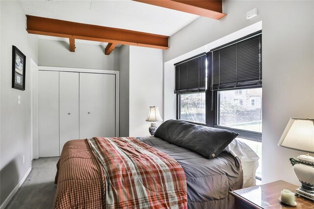 bedroom featuring beamed ceiling, a closet, and carpet