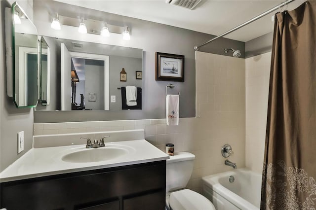 full bathroom with tile walls, shower / bath combo with shower curtain, toilet, and vanity