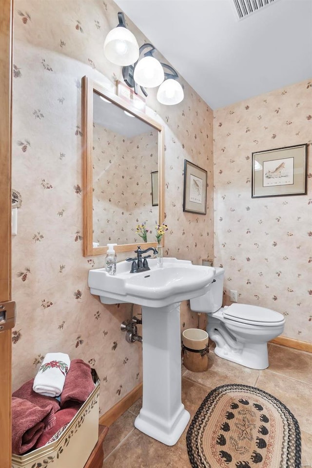 half bathroom with tile patterned flooring, visible vents, baseboards, and wallpapered walls