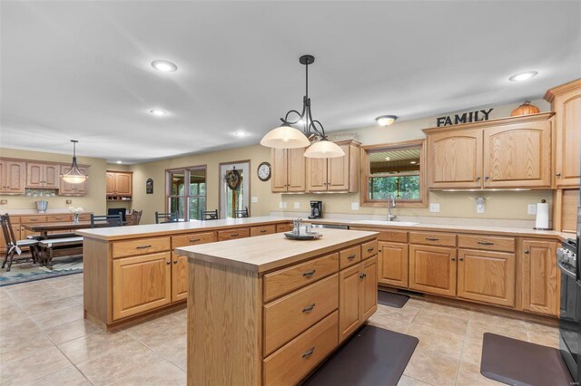 kitchen featuring sink, kitchen peninsula, pendant lighting, light tile patterned flooring, and a center island