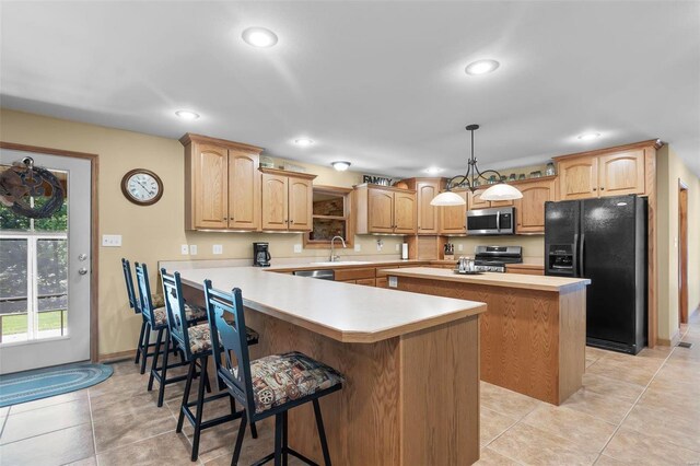 kitchen featuring light tile patterned flooring, stainless steel appliances, hanging light fixtures, a breakfast bar area, and kitchen peninsula