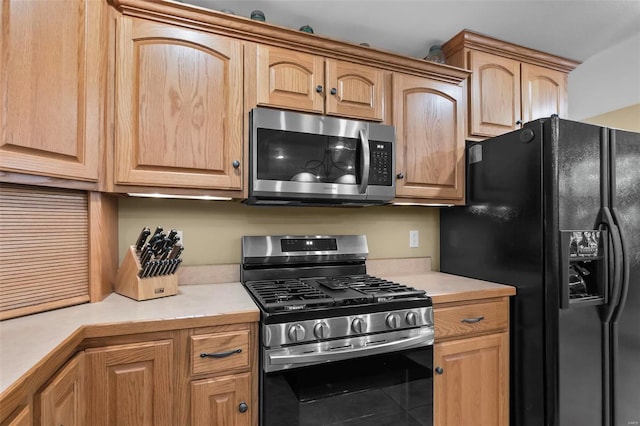 kitchen with tile patterned floors, stainless steel appliances, light countertops, and light brown cabinetry