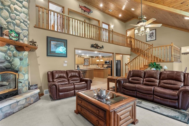 living room featuring a stone fireplace, a towering ceiling, wood ceiling, and light colored carpet